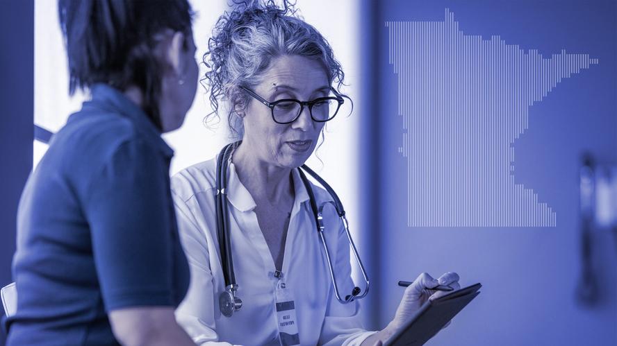 A female medical practitioner with a stethoscope and note pad discusses a health matter with a female patient. Photo by FatCamera/Getty Images