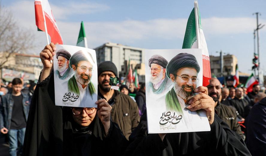 People hold placards with an image of Iran's new Supreme Leader Mojtaba Khamenei with his late father, Ayatollah Ali Khamenei, in Tehran, Iran, March 9, 2026