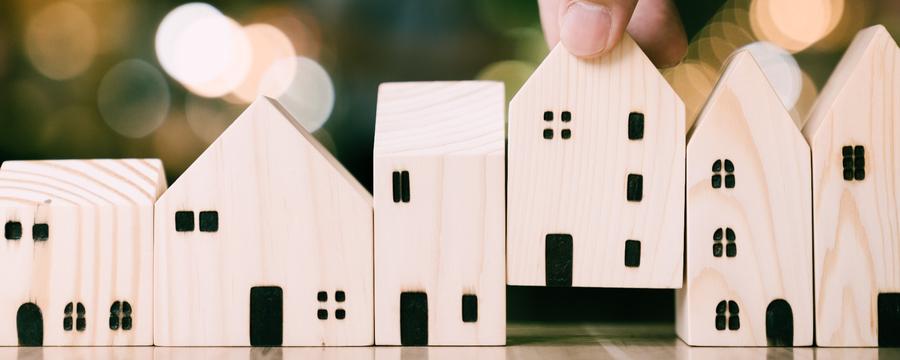 House-shaped wooden blocks being placed in a row. Photo by Getty Images