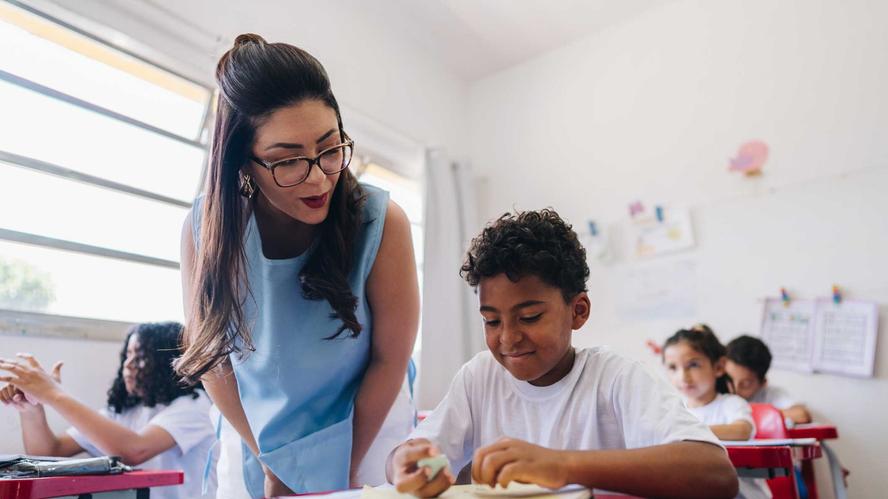 Teacher teaching her student on classroom at school