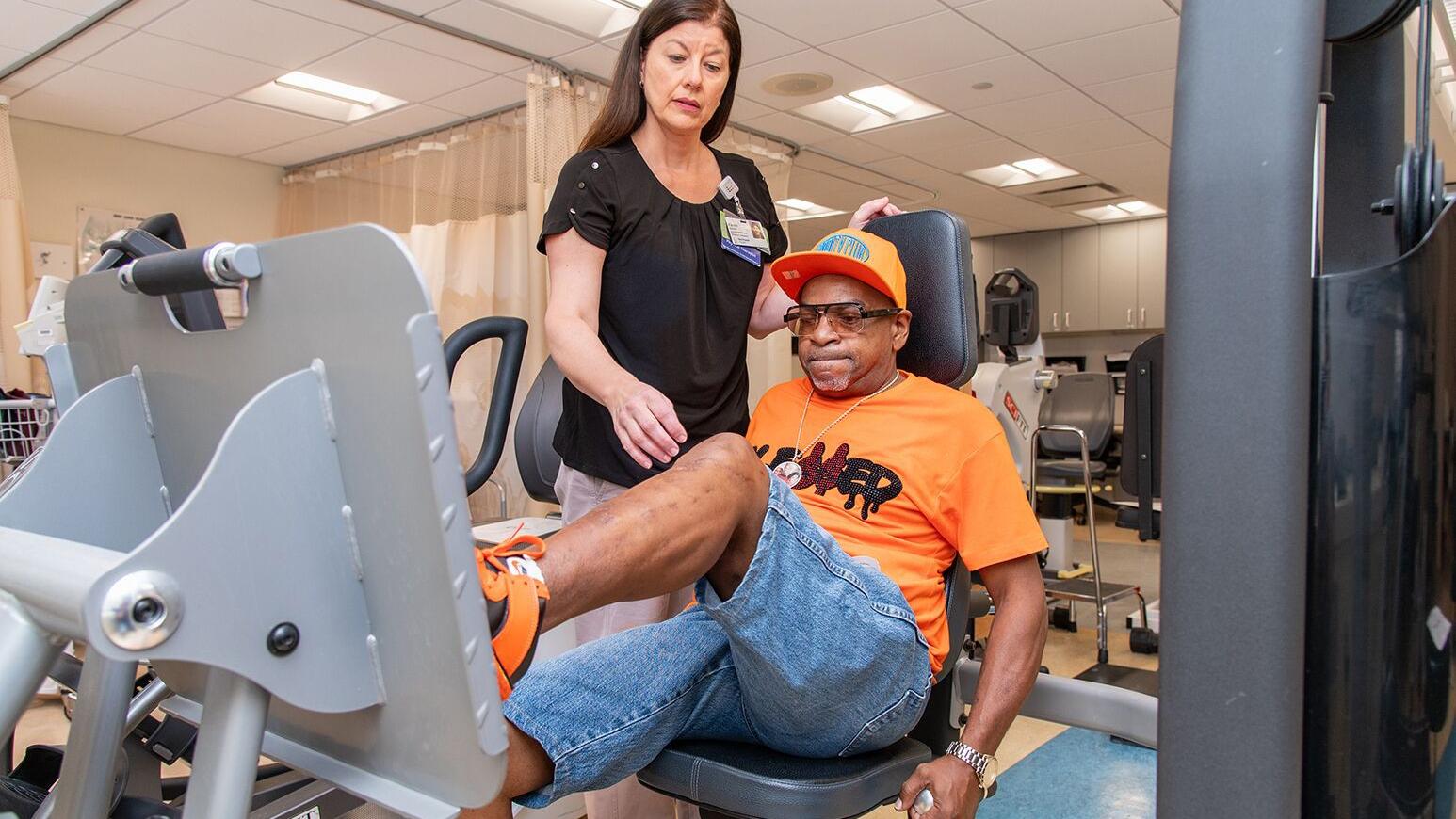 A female physical therapist watches as an older man works out on leg press machine. Photo by Northwell Health